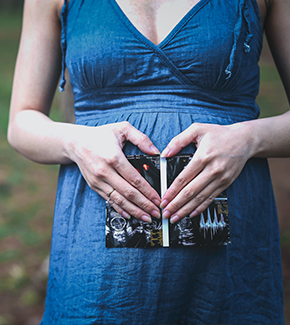 Pregnant woman holding ultrasound image over her belly.